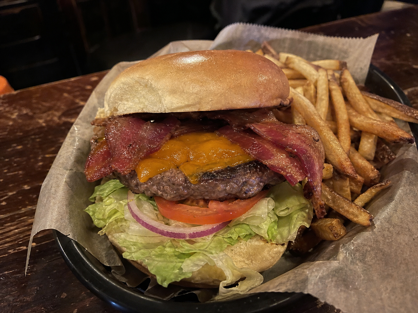 Bacon cheeseburger with lettuce, tomato, onion and fries