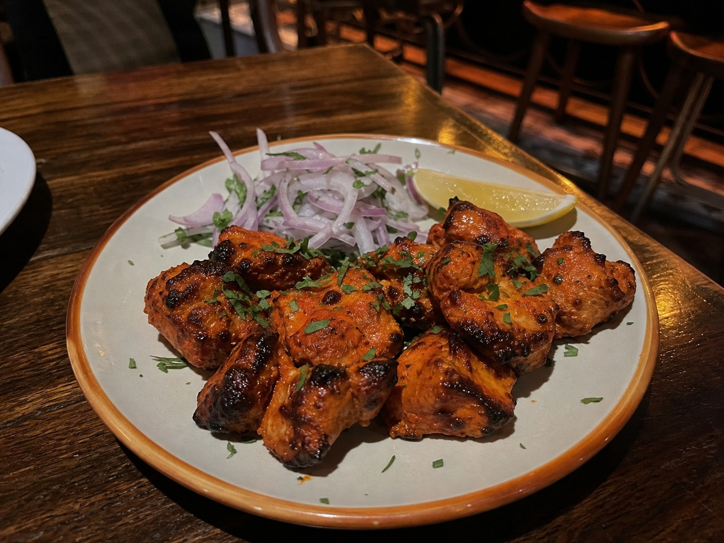 Grilled chicken tikka with charred edges, onion and lemon