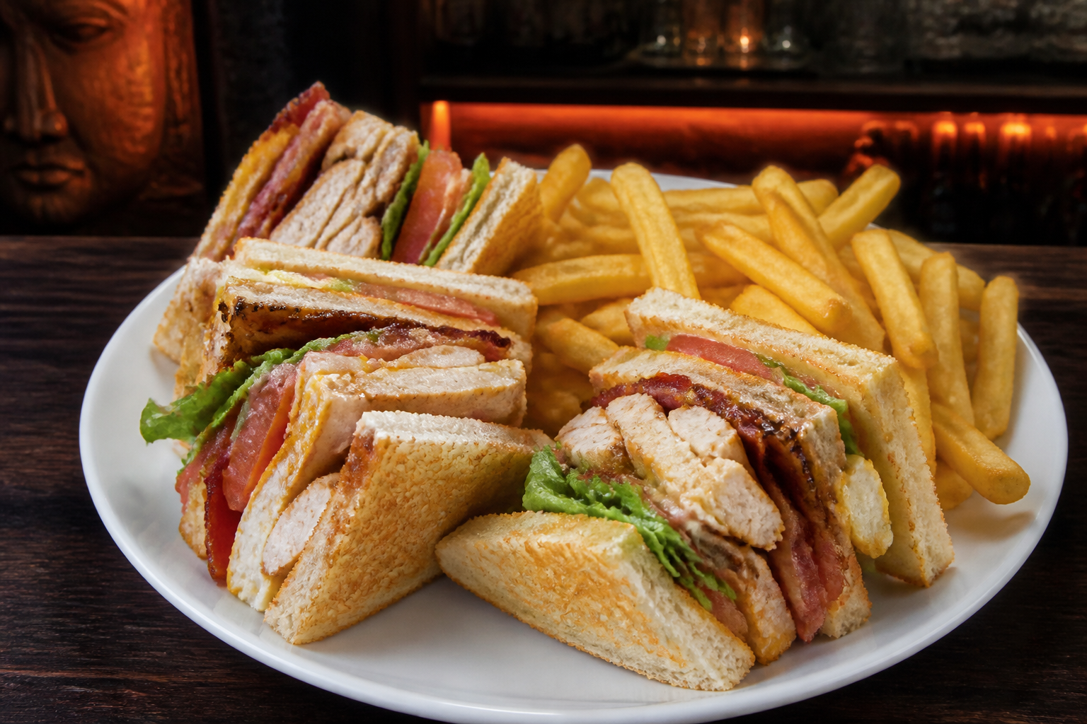 Club sandwich with grilled chicken, bacon, fried egg, lettuce, tomato and fries