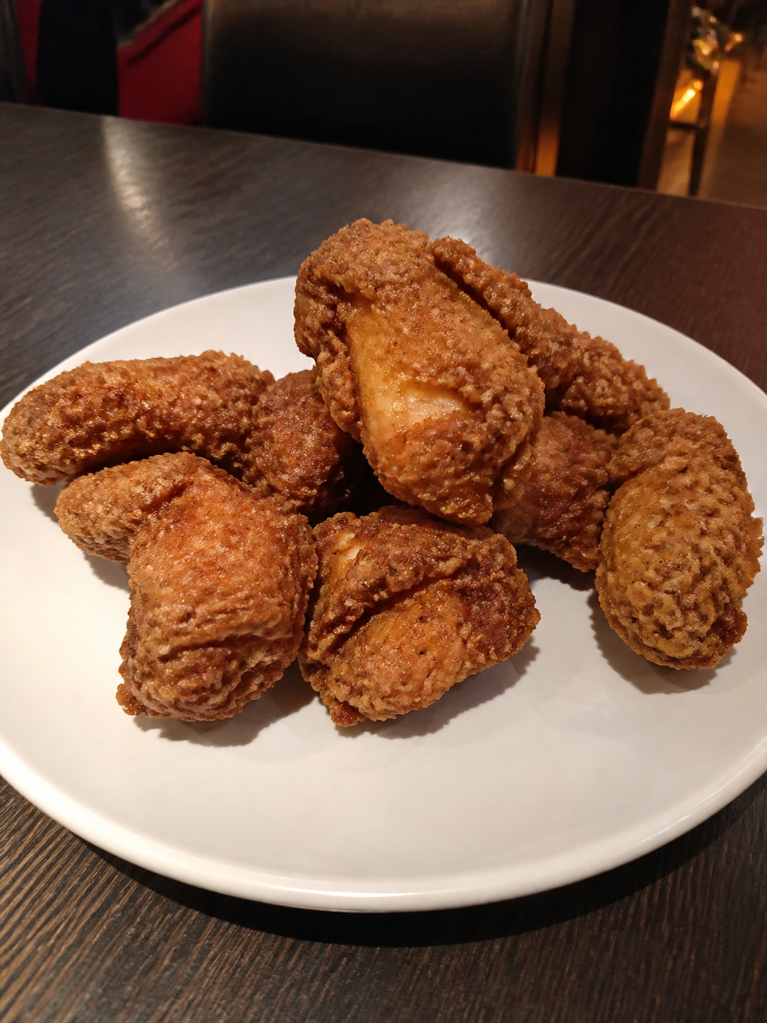 Fully cooked crispy fried chicken pieces on a white ceramic plate