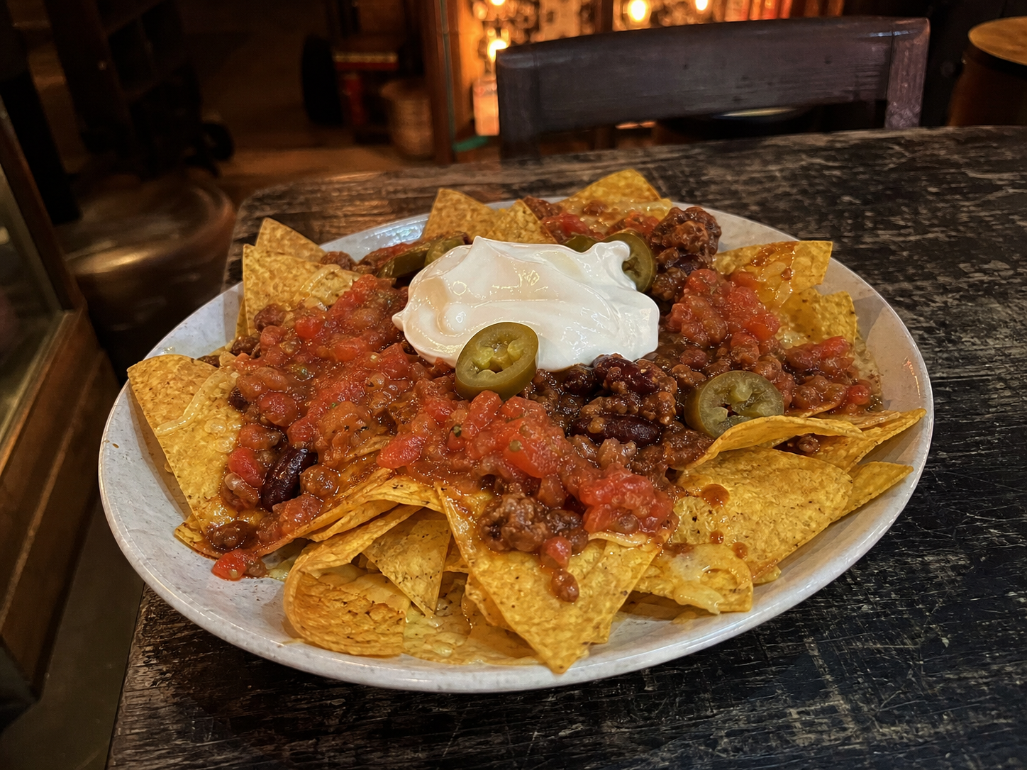 Nachos with chilli con carne, salsa, sour cream and jalapenos