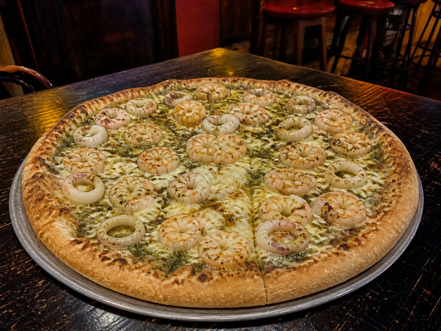 Pesto seafood pizza with cooked prawns, squid and melted mozzarella