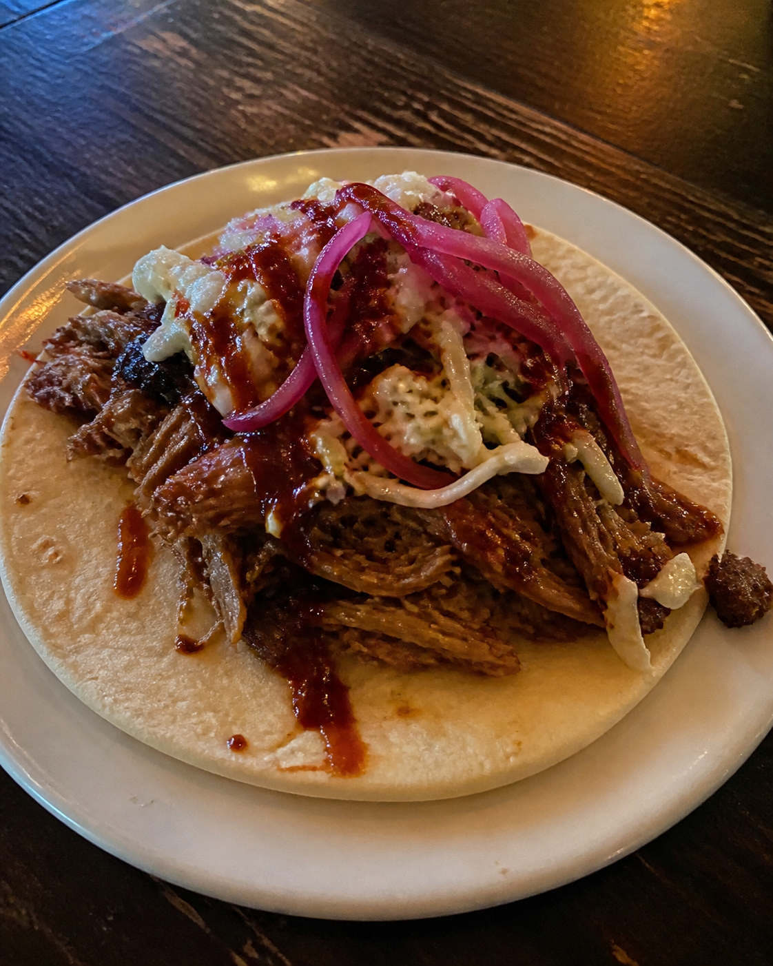 Pulled pork taco with slaw and pickled onion