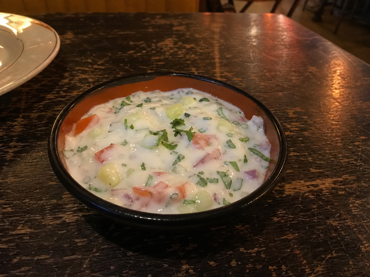 Raita yogurt with cucumber, tomato, onion and herbs