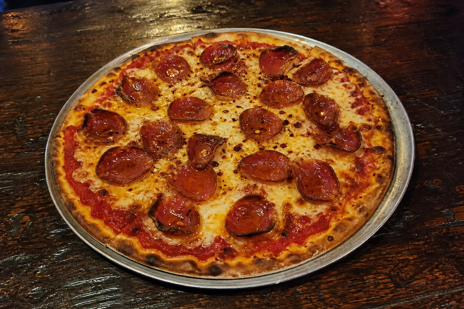 Thin-crust spicy salami pizza with chilli flakes