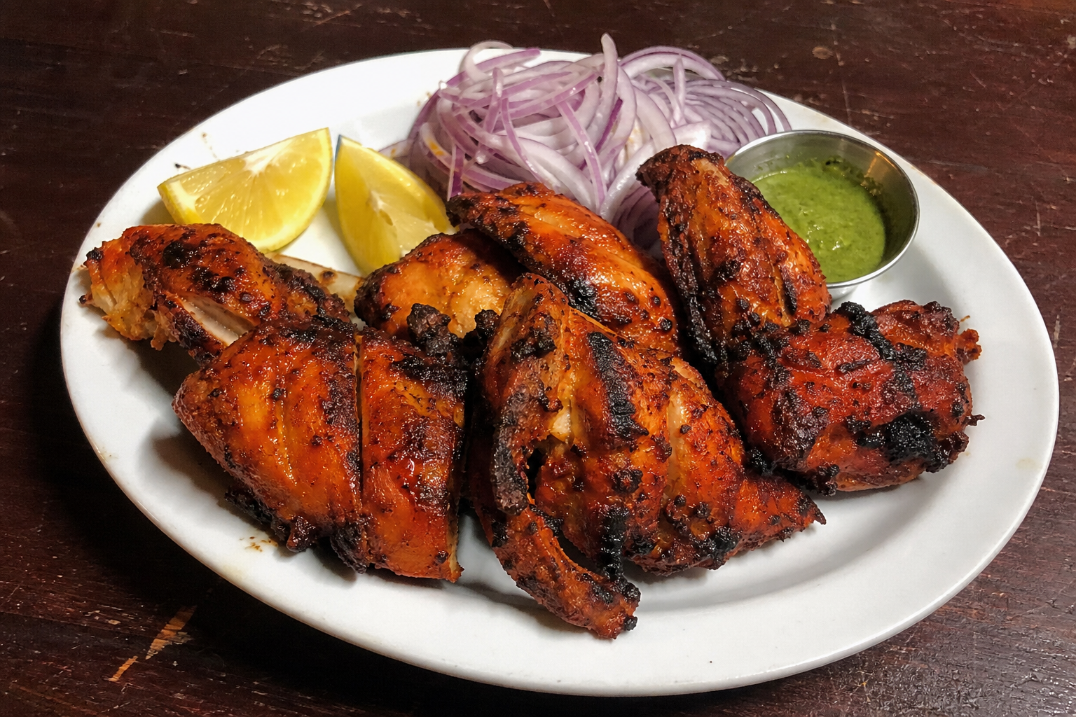 Tandoori chicken with charred edges, onion and lemon